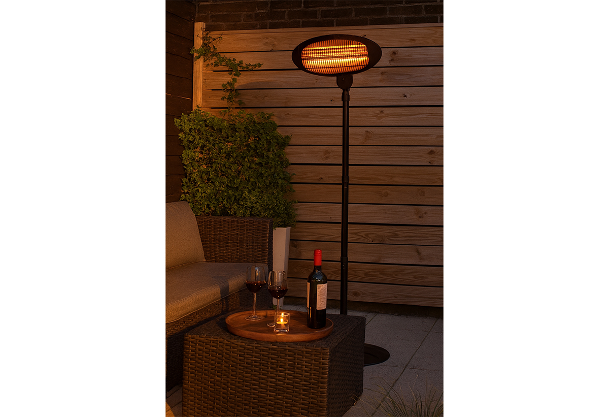 Απεικονίζεται η θερμάστρα σε εξωτερικό χώρο, δίπλα σε τραπεζάκι με κρασί.